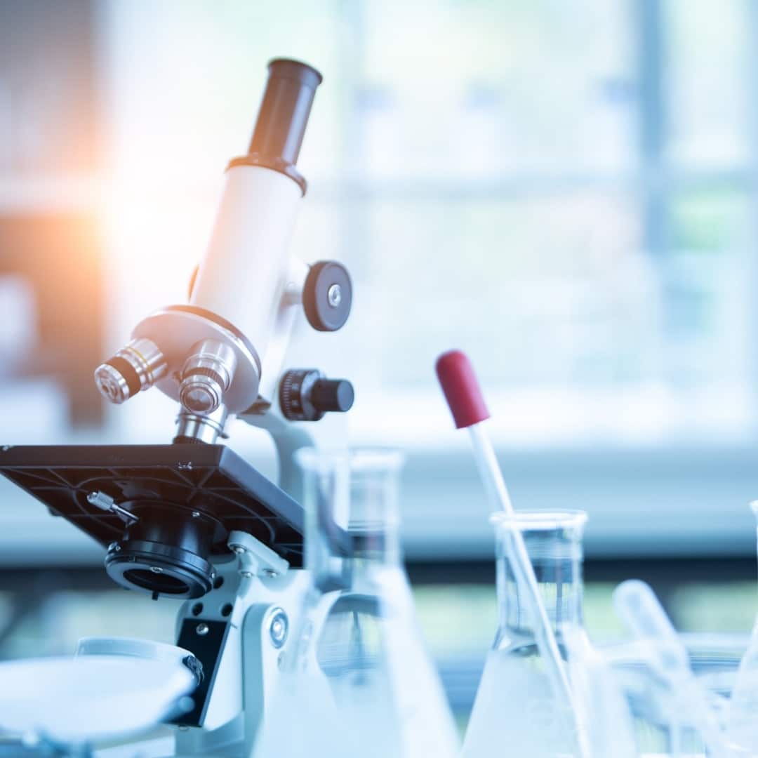 a microscope placed on a table next to a glass tube